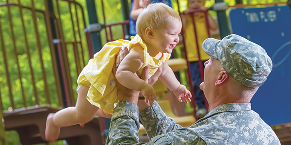 soldier holding baby daughter in the air